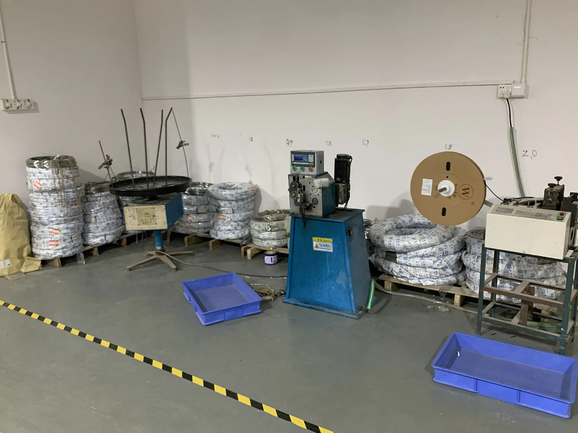 Brush manufacturing production line with wire feeding equipment and coiled metal stock prepared for brush production.
